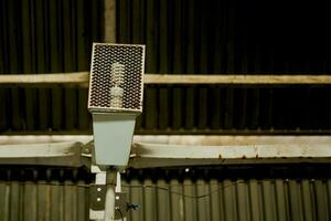 Industrial light bulb in a protective wire cage, mounted at the metal wall photo