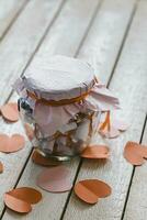 Glass jar on wood. Valentine's day concept. Date Jar with desires. Red paper hearts at background. photo