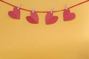 Red hearts on rope with clothespins on yellow. Place for text, copy space photo