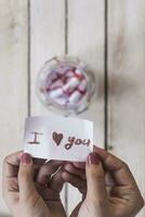 I Love you text on rolled paper. Female opening a gift glass jar with wishes photo