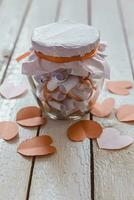 Glass jar on wood. Valentine's day concept. Date Jar with desires. Red paper hearts at background. photo