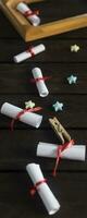 Flat lay romantic background. Giftbox, rolled wish papers, and wooden frame with paper hearts on dark wood board. photo