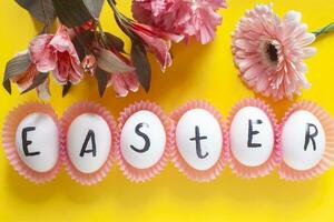 Happy Easter. Easter text on white eggs with spring flowers photo