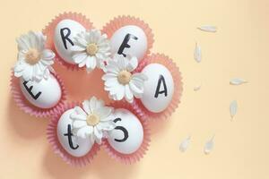 Happy Easter. Easter text on white eggs with spring flowers photo