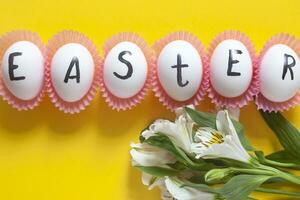 Happy Easter. Easter text on white eggs with spring flowers photo