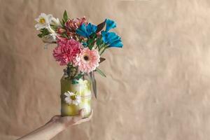 Woman holding up a glass jar full with colorful spring flowers photo