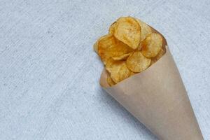 A paper cone full of potato chips photo
