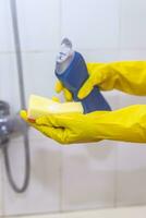 Woman in gloves putting cleaning chemistry to the sponge and want to clean up the bathroom photo