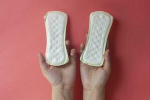 Woman's hands holding two feminine hygiene pads. Hands of female hold menstrual pads or sanitary napkins for women photo