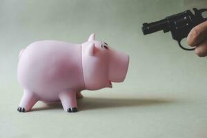 pink piggy bank and hand with gun photo