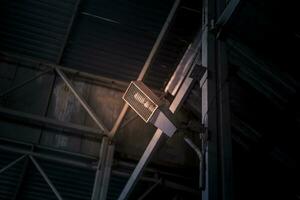 Industrial light bulb in a protective wire cage, mounted at the metal wall photo