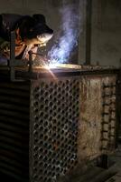 Man welds metal. Worker welding steel in industry with safety mask safety gloves and safety equipment. Metal industry welding concept photo