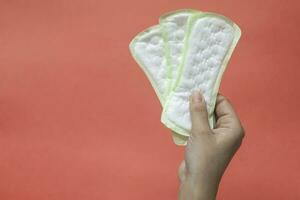 woman's hands holding feminine hygiene pads. Hands of female hold menstrual pads or sanitary napkins for women photo