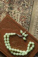 The Holy Quran with rosary and praying carpet. Image of The Holy Quran with rosary. Muslim Rosary Beads And Quran. Flat lay view photo