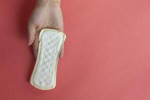 Woman's hands holding a feminine hygiene pad. Hands of female hold menstrual pads or sanitary napkins for women photo