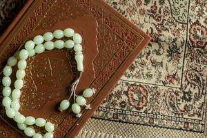 The Holy Quran with rosary and praying carpet. Image of The Holy Quran with rosary. Muslim Rosary Beads And Quran. Flat lay view photo