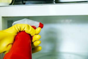 Woman hands in rubber gloves washing microwave photo