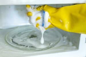 Woman hands in rubber gloves washing microwave photo