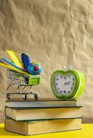 Back to school concept. Stack of books with school supplies in shopping cart photo