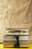 Back to school concept. Stack of books and a tie with a glasses photo