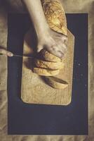 Food concept. Hand cutting bread. Slicing a bread. Top view. photo