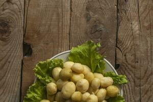 A plate of boiled new fresh potatoes on wooden background. Free space photo