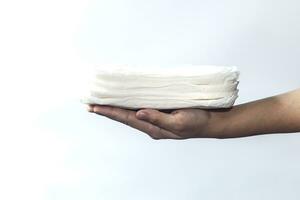 mujer mano participación un apilar de sanitario servilletas en contra blanco antecedentes. período dias concepto demostración femenino menstrual ciclo. foto