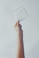 A woman put hands up holding a sanitary napkin against white background. Period days concept showing feminine menstrual cycle. photo