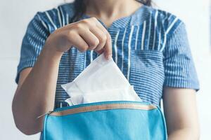 Young women taking sanitary pads inside of her cosmetic bag on blue background photo