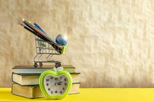 Back to school concept. Stack of books with school supplies in shopping cart photo