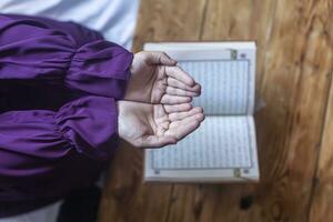 Praying young muslim woman. Middle eastern girl praying and reading the holy Quran. Muslim woman studying The Quran photo