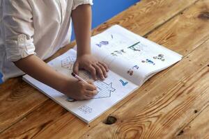 Preschool age child doing the math. Little boy doing homework. Drawing on kid notepad. Free space photo