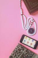 Translation The Holy Quran. Traditional muslim prayer set bundle. Praying carpet, rosary beads, little version of the Holy Quran and qibla compass on wooden background. Free Space photo