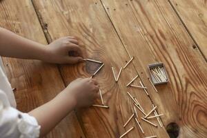 A boy playing with matchsticks. Young kid plays match sticks on wooden background. photo