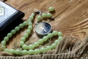 Traditional muslim prayer set bundle. Praying carpet, rosary beads, little version of the Holy Quran and qibla compass on wooden background. Free Space photo