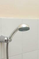 Showerhead in the bath. Hanging shower head in the old style bathroom with tile walls photo