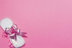 A sanitary pad tied with ribbon on the pink background. Medicine, women health and ovulation concept photo
