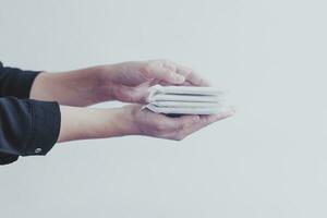 Female's hygiene products. Woman's hand holding a stack of sanitary napkins against white background. Period days concept showing feminine menstrual cycle. photo