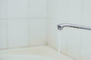 Bathroom. Open bath water tap with running water. photo