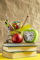 Back to school concept. Stack of books with school supplies in shopping cart photo