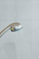 Showerhead with flowing water. Water running from the head of the shower in the bath photo