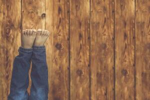 Young boy lying on his bed. A kid having fun. A little child raising his legs against the wooden desk. photo