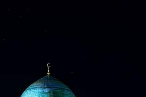 The golden crescent on the dome of the Mosque. Waxing moon - a symbol of Islam at the top of the temple at night sky with stars. Free space. For Ramadan and Eid background photo