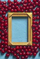 de madera marco con Copiar espacio y maduro cerezas en azul antecedentes. bayas y frutas alrededor el vacío madera marco foto