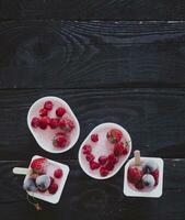 Homemade fresh yogurt. Healthy sweet dessert on dark rustic wood. Frozen fruits photo