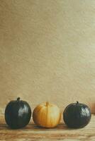 Colored halloween pumpkins on wooden desk. Difference. Alone among the others. Single orange pumpkin in a row of black pumpkins photo