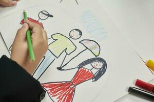 Family therapy. Schoolboy drawing family. Painting with colored marker photo