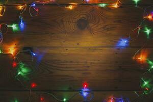 Christmas decorative lights. Christmas garland lights on wood. Colorful Xmas light bulbs on rustic brown plank photo
