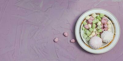 Plate of Marshmallows on pink background. Colorful marshmallow sweets with copy space photo