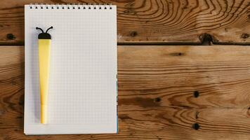 Blank notepad with funny yellow pen on wooden desktop photo